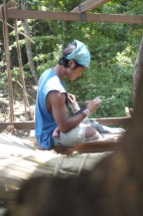 Wira uses his parang (machete) to make strings from vines.